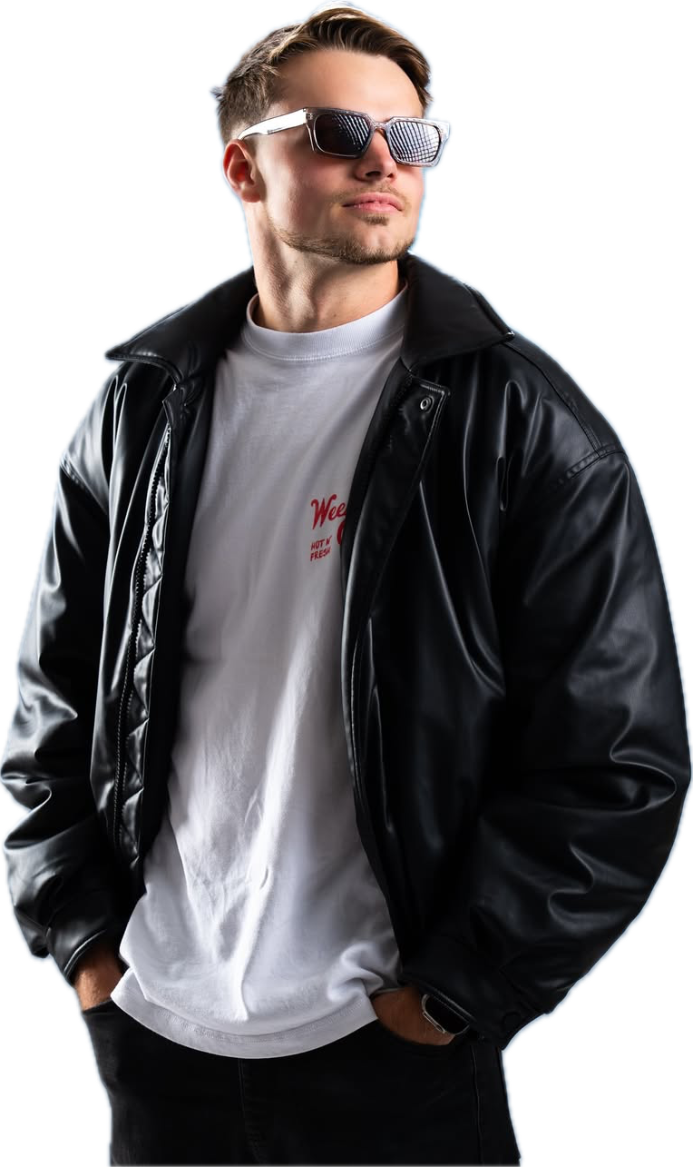 Davon Goodchild looking down at the camera, sunglasses in hand, wearing a black jacket