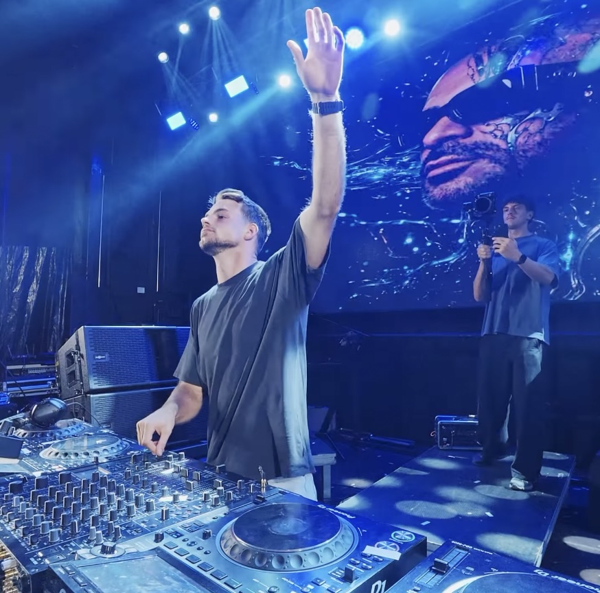 DJ performing on a large stage under blue lights